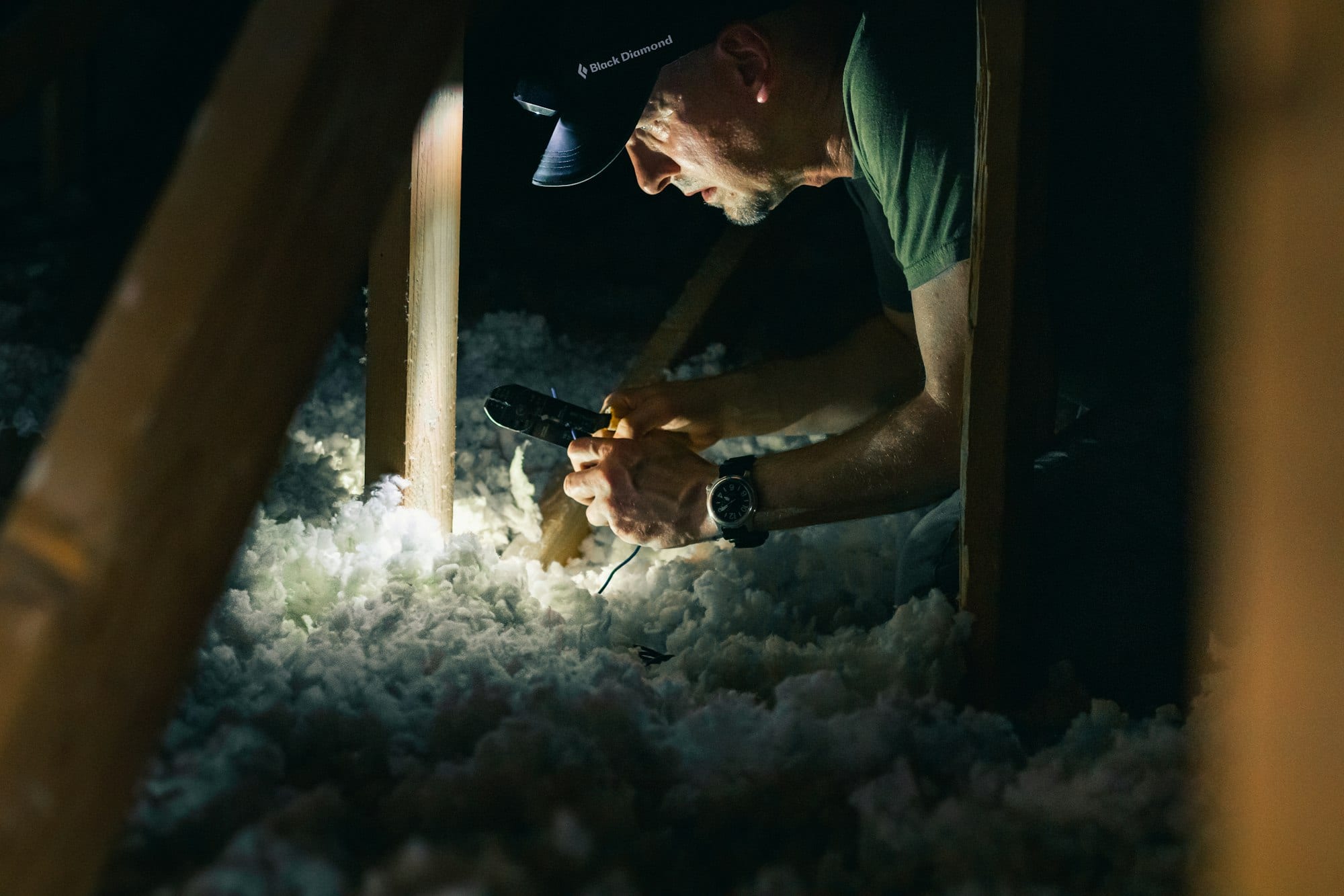 Artisan vérifiant l'isolation des combles à la lampe
