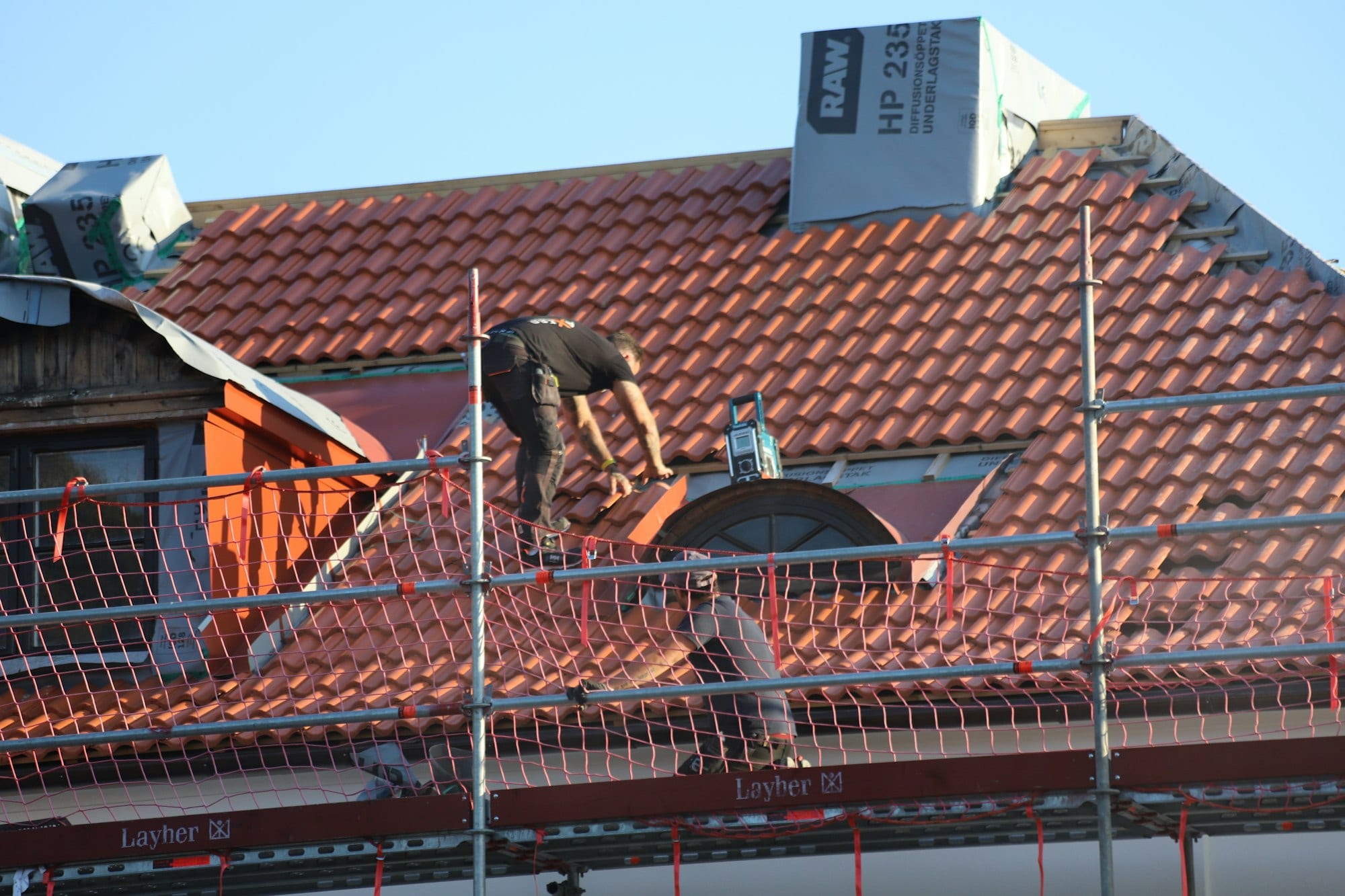 Couvreur au travail sur un toit en tuiles