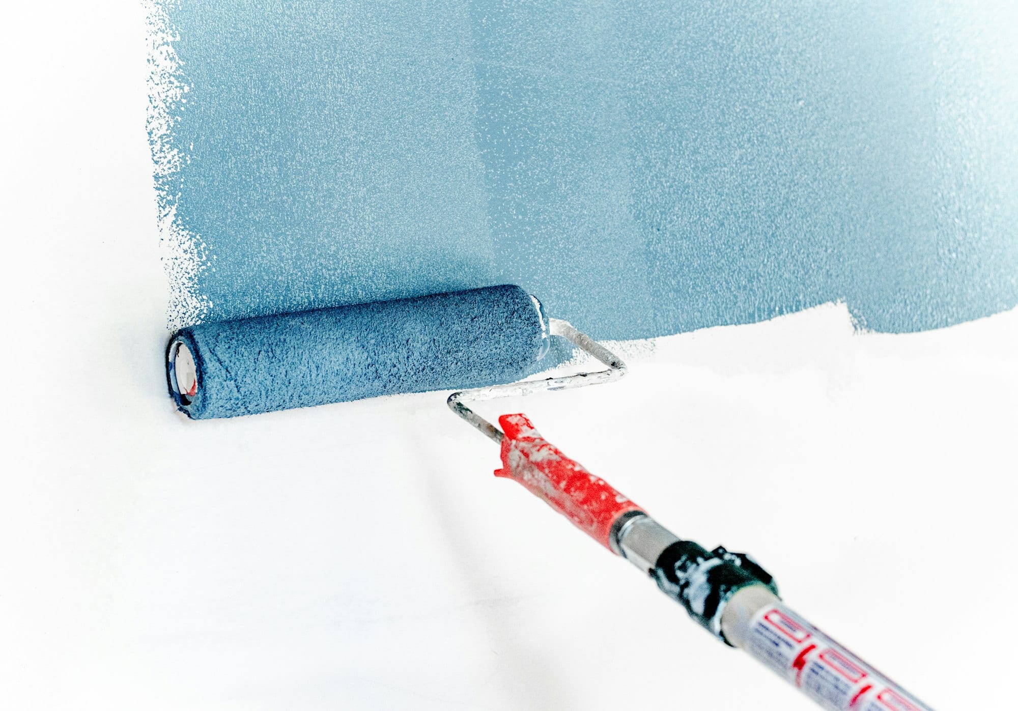 Rouleau appliquant une peinture bleue sur un mur blanc
