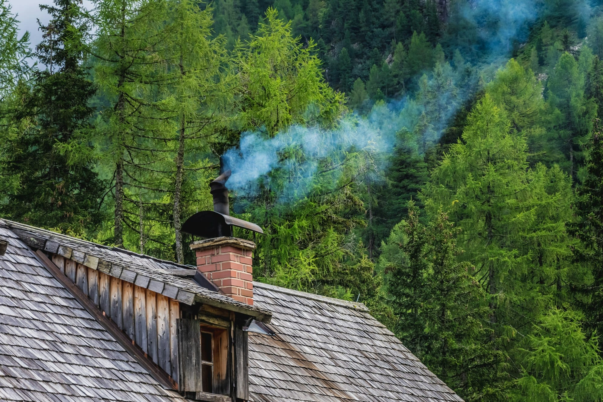 Cheminée qui fume sur un toit de chalet en forêt